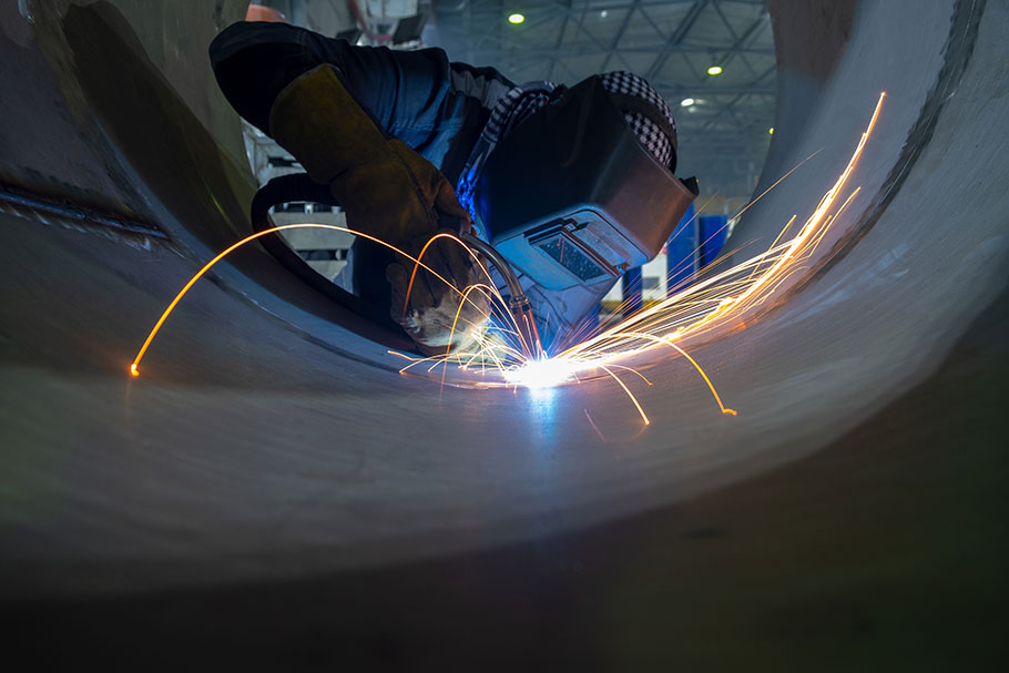 Welder working inside a large stainless steel vessel at the Aquafil factory